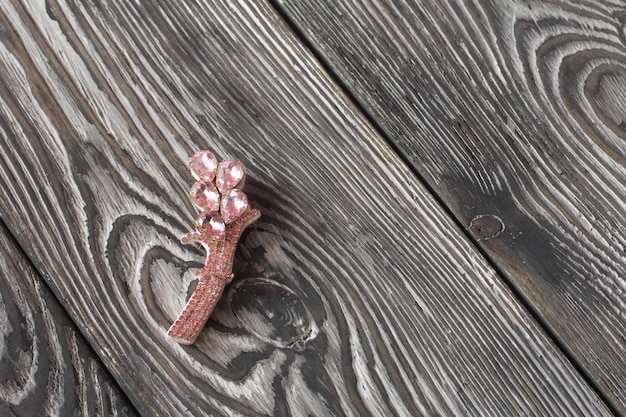 Foto handgefertigte brosche rosa farbe liegt auf kiefernbrettern