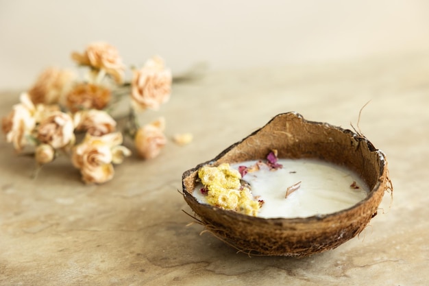 Handgefertigte Kerze aus Soja- und Kokoswachs in Glas mit Holzdocht und Trockenblumen isoliert auf pastellbeigem Hintergrund Flach liegender Kopierraum mit Draufsicht