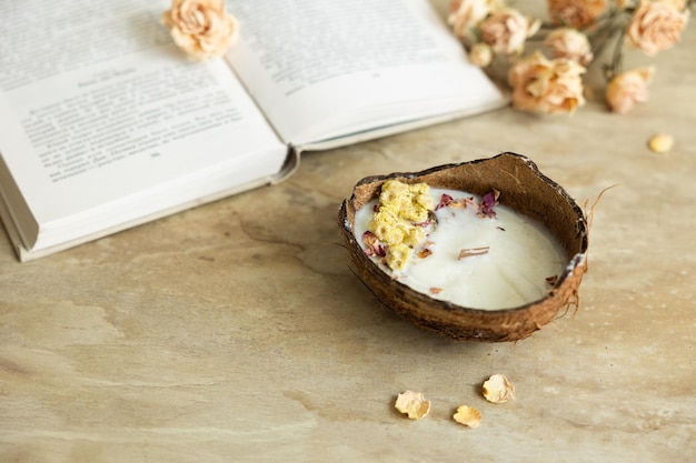 Handgefertigte Kerze aus Soja- und Kokoswachs in Glas mit Holzdocht und Trockenblumen isoliert auf pastellbeigem Hintergrund Flach liegender Kopierraum mit Draufsicht