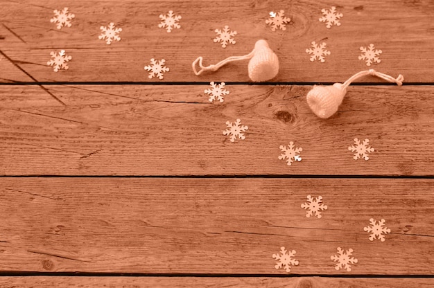 Handgefertigte Weihnachtsspielzeuge liegen auf einem hölzernen Hintergrund weiße Hüte gestrickt aus Wolle machen Sie es selbst Pfirsich Fuzz ist die Farbe des Jahres 2024 getönte Bild