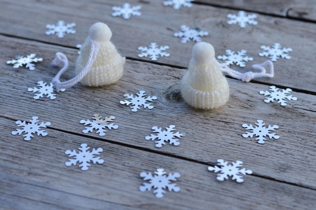Handgefertigte Weihnachtsspielzeuge liegen auf einem hölzernen Hintergrund, weiße Mützen aus Wolle gestrickt zum Selbermachen