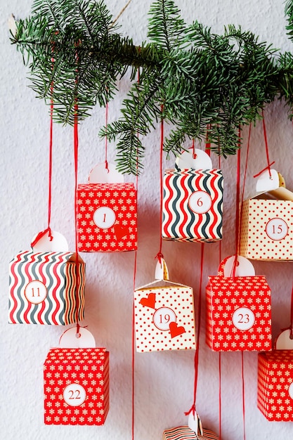 Foto handgefertigter adventskalender, rote geschenkkisten, die an der wand hängen, nachhaltige weihnachts-close-up