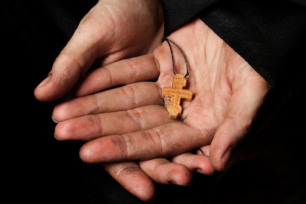 Handgefertigtes Holzkreuz in der Handfläche einer Bäuerin. Nahaufnahme