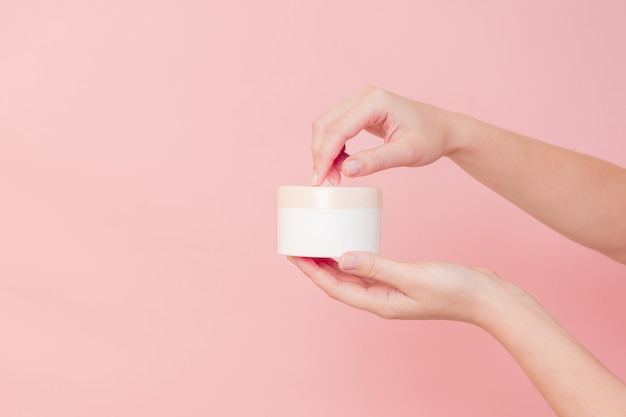 Handgehaltes Glas mit Kosmetikcreme auf rosa Hintergrund Kosmetik-Beauty-Mockup für Produktbranding