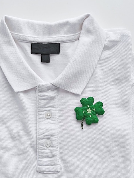 Handgemachte Kleeblattbrosche auf weißem T-Shirt. Das Konzept zum St. Patrick's Day feiern