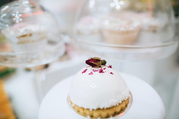 Handgemachte köstliche Kuchen mit Knospenrosen, dekoriert an einem Hochzeitsdesserttisch Ideax9