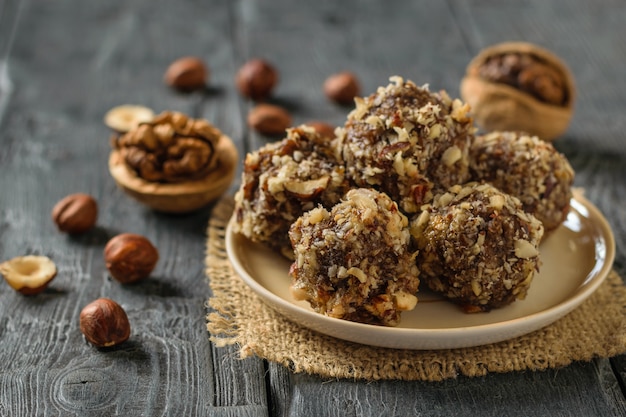 Handgemachte Kugeln aus getrockneten Früchten, Nüssen und Schokolade auf einem Holztisch.