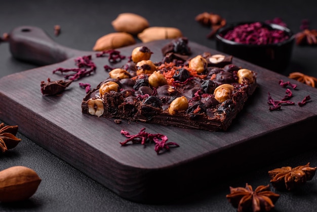 Handgemachte Schokolade mit Beeren, Nüssen und Gewürzen auf dunklem Hintergrund