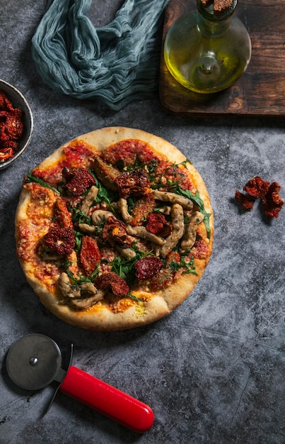 Handgemachte vegane Pizza mit Tofu, sonnengetrockneten Tomaten und Rucola