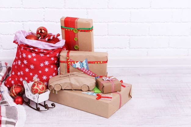 Handgemachte Weihnachtsgeschenke und Weihnachtstüte mit Kugeln auf dem Boden im Zimmer