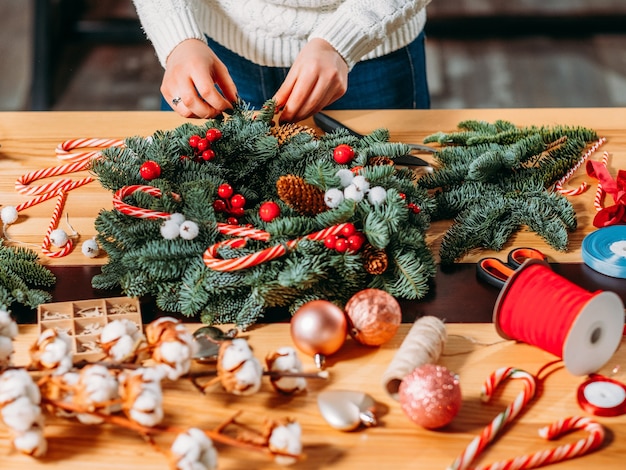 Handgemachter Weihnachtskranz. Floristin, die an neuer Winterdekoration arbeitet.