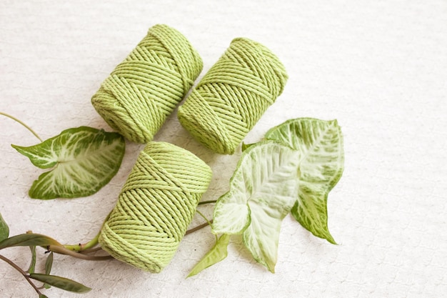 Handgemachtes Makramee-Geflecht und Baumwollfäden auf weißem Textilhintergrund Grüne Makramee-Schnüre und Seile aus Baumwolle