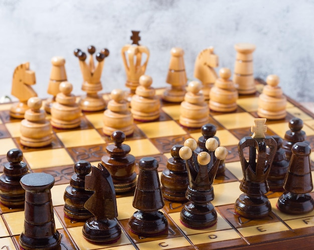Handgeschnitzte Schachfiguren auf einem handgefertigten Holzschachbrett. Geschäftsstrategie, Taktikkonzept