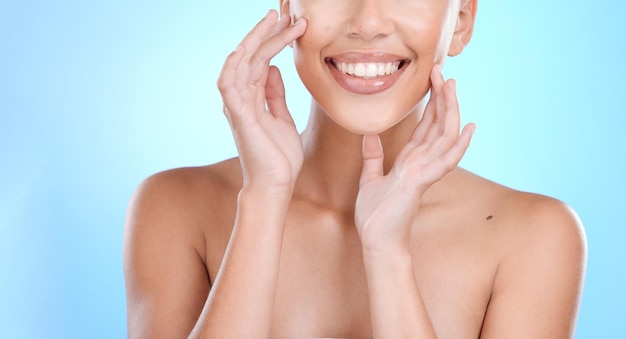 Handgesicht und berührende Haut mit einer Modellfrau im Studio auf blauem Hintergrund für Schönheit oder Hautpflege Hände berühren und Gesichtsbehandlung mit einer jungen Frau im Innenbereich, um ein Anti-Aging-Kosmetikprodukt zu fördern