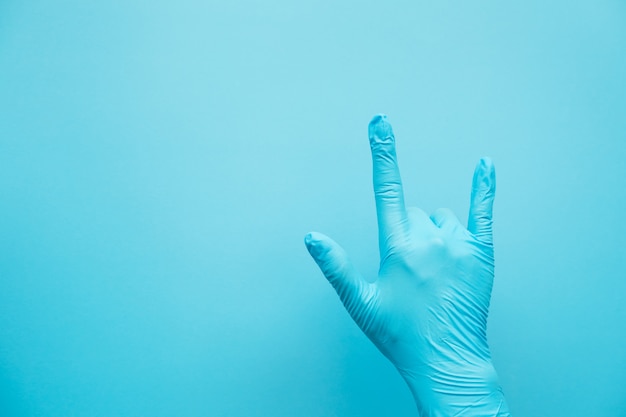 Foto handgeste des arztes, der blaue handschuhe auf blauem hintergrund trägt, zeichen für liebe