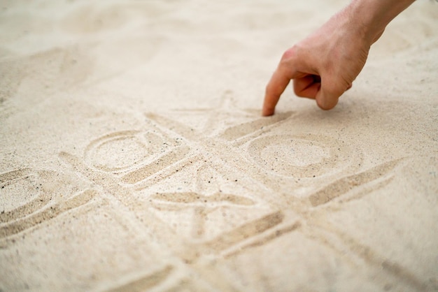 Handgezeichnetes Tic-Tac-Toe-Spielen im Sand am Sommerstrand