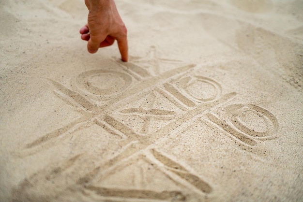 Handgezeichnetes Tic-Tac-Toe-Spielen im Sand am Sommerstrand