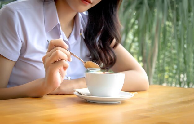 Handgrifflöffel, um heißen Kaffeeschaum auf Keramikschale zu mischen