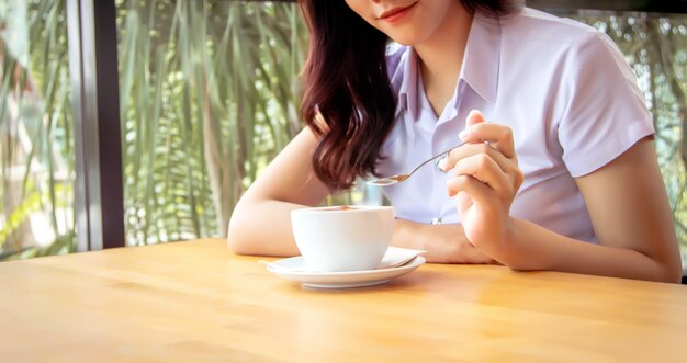 Handgrifflöffel, um heißen Kaffeeschaum auf Keramikschale zu mischen