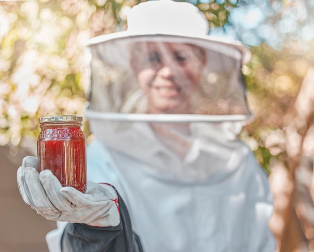 Handhonig und Glas mit einer Imkerin, die auf dem Land bei der Herstellung eines Naturprodukts arbeitet Landwirtschaftliche Landwirtschaft und Nachhaltigkeit mit einer Bäuerin, die ein Honigglas im Freien hält