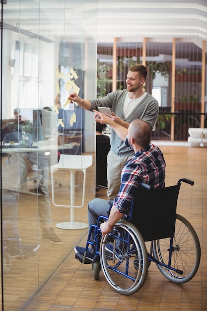 Handikapgeschäftsmann, der Kollegen im kreativen Büro unterstützt