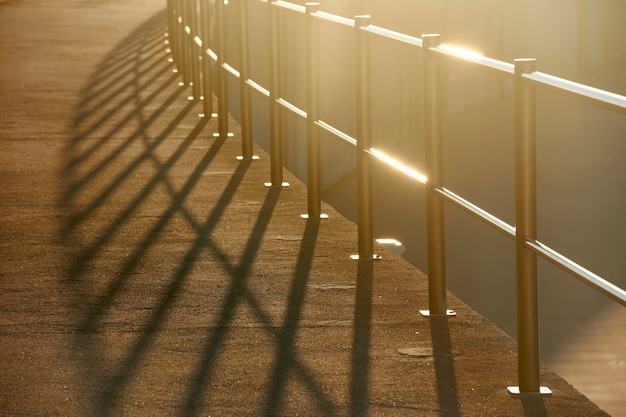 Foto handlauf aus metall wirft harte schatten auf den betonweg