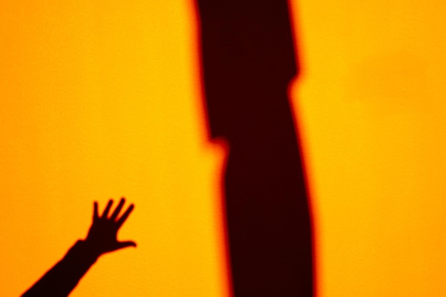 Handschatten vor der orangefarbenen Wand