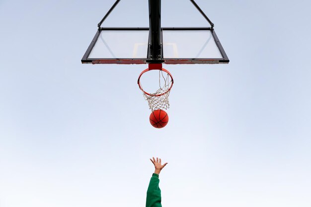 Handschießen in einem Basketballkorb von unten gesehen mit dem Himmel im Hintergrund Konzept des urbanen Sports im Freien Platz für Text kopieren