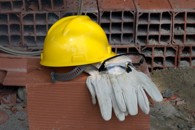 Handschuhe, Helm und Maurerbrille auf Ziegelhaufen