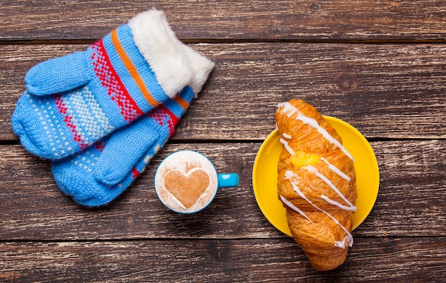 Handschuhe und Tasse Kaffee auf Holztisch.