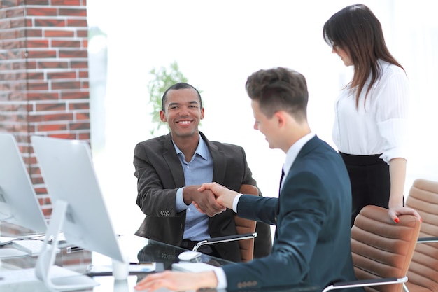 Handshake-Geschäftsleute hinter einem Schreibtisch im Büro