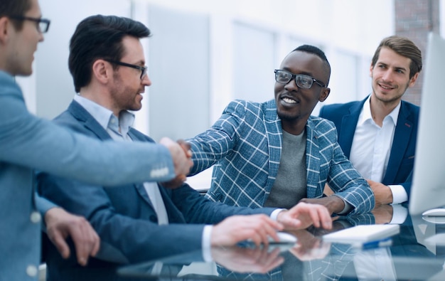 Handshake-Kollegen, die am Schreibtisch sitzen, das Konzept der Zusammenarbeit