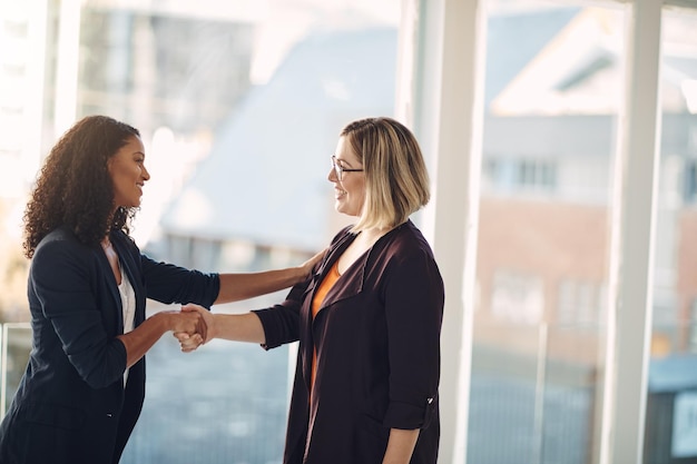 Foto handshake-meeting und erfolgreicher manager begrüßen förderung und vereinbarung mit einem sprechenden unternehmenskollegen lächelndes team selbstbewusster professioneller frauen, die zusammenarbeiten und teamarbeit im büro zeigen