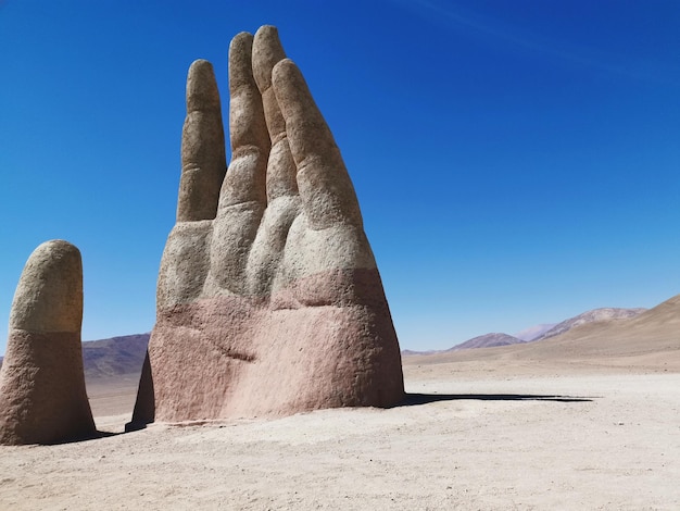 Foto handskulptur in der wüste vor klarem blauen himmel