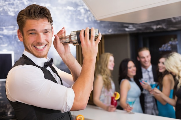 Handsome barman sorrindo para a câmera fazendo um cocktail