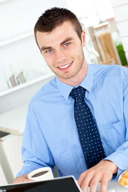 Handsome businessman usando um laptop na cozinha