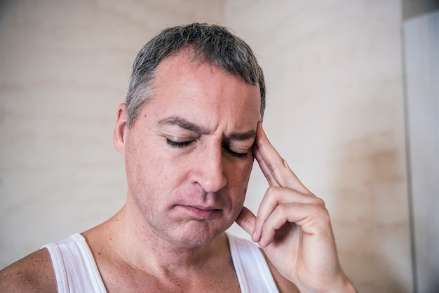 Handsome junge Mann berührt seinen Kopf mit einer Hand Gefühl starke Kopfschmerzen, close up Foto. Fühle mich müde. Stress, Kopfschmerzen, Verzweiflung, Trauer und Menschen Konzept