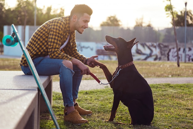 Handsome junge Mann spielt mit seinem Hund im Park.