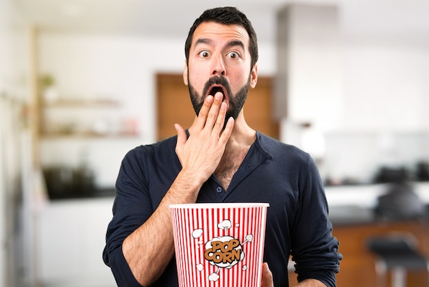 Handsome Mann mit Bart essen Popcorns im Haus