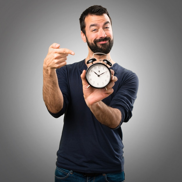 Handsome Mann mit Bart halten Vintage Uhr auf grauem Hintergrund