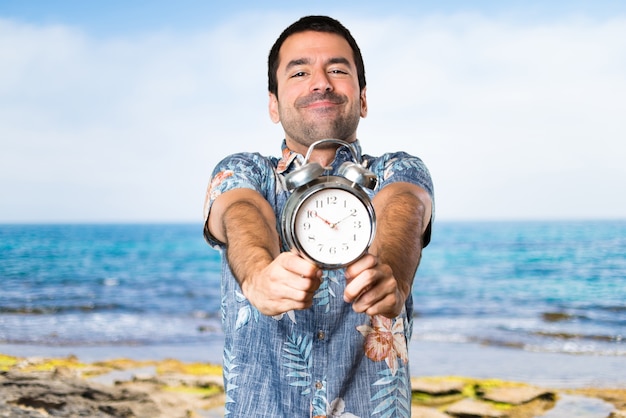 Handsome mann mit blumen-shirt mit vintage-uhr am strand