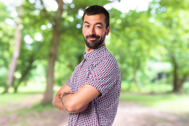 Handsome Mann mit seinen Armen auf unfocused Hintergrund gekreuzt