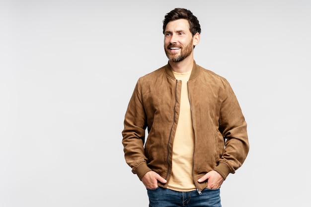 Foto handsome smiling bearded man wearing brown autumn jacket stylish jeans isolated on grey background