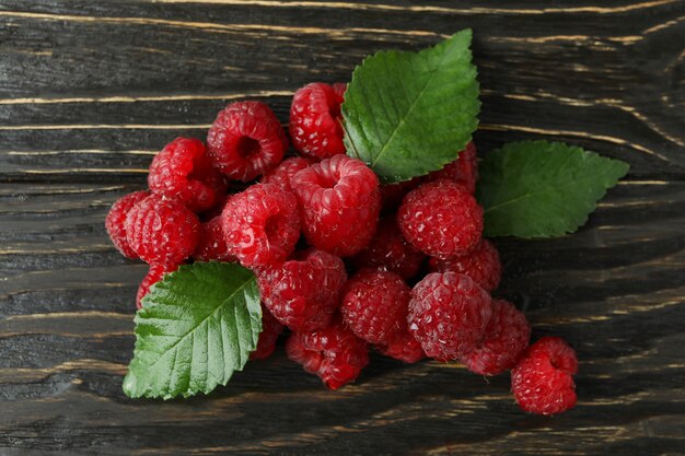 Handvoll Himbeeren mit Blättern auf Holzhintergrund.