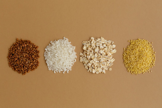 Handvoll verschiedener Getreide auf braunem Hintergrund. Reis und Haferflocken, Buchweizen und Hirse