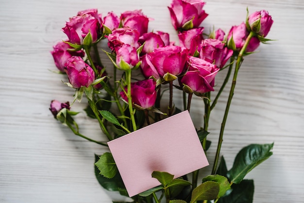 Handwerk rosa Postkarte mit Strauß kleiner Rosen auf Holzhintergrund Platz für Textnachricht Frühlingsblumen Feiertagsgrußkarte zum Valentinstag Frauen Muttertag Ostern Draufsicht flach liegen