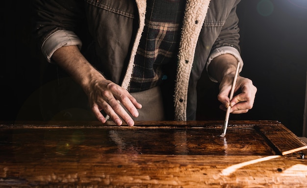 Handwerker arbeitet in einer Werkstatt mit Holzlacken ein Holzelement von Möbeln