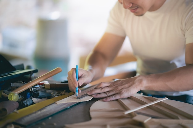 Handwerker, der Gitarre auf Holztisch, Capenter-Arbeitskonzept macht