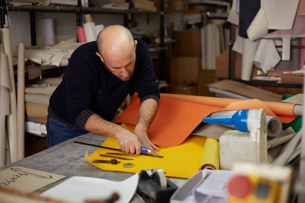 Handwerker, der Leder mit Cutter in der Werkstatt schneidet