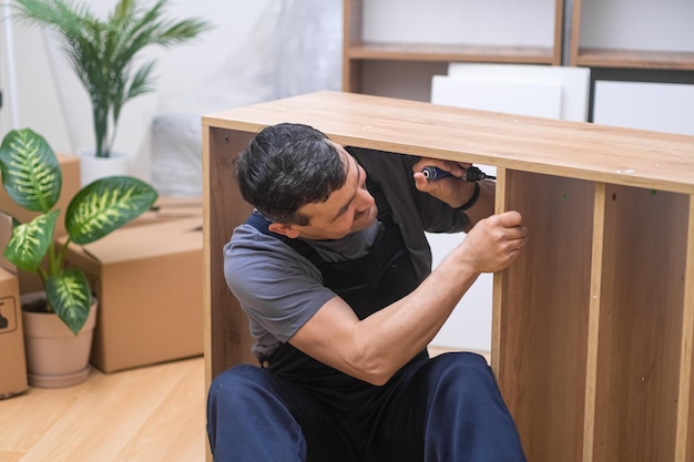 Handwerker eines maßgefertigten Möbelgeschäfts, der Holzregale zusammenbaut und Nägel festzieht
